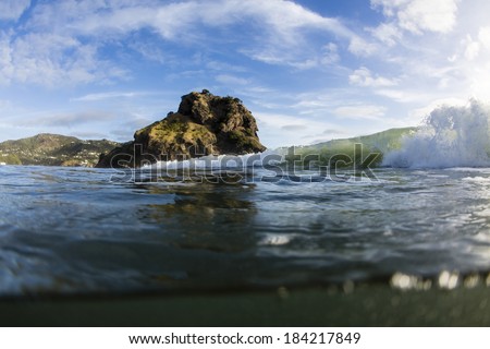 Piha Waves/ a wave breaks in front of Piha Beach\'s iconic Lion Rock