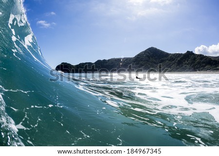 Breaking Surf/ perfect wave for surfing breaks, shot from the surf, inside the wave at Piha Beach, New Zealand