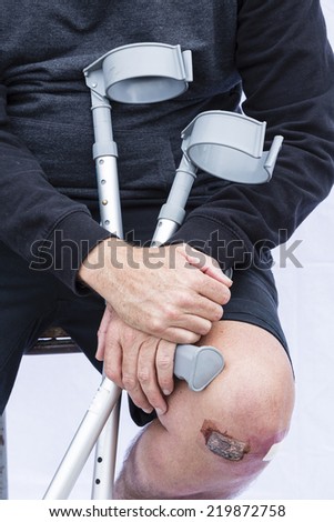 Crutches and knee/ a close crop of a man\'s injured knee with crutches