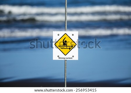 Strong Current/ a strong current warning sign on a beach.