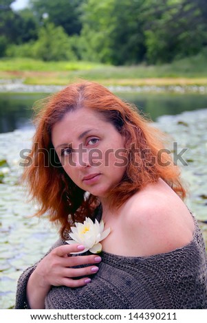 Portrait of beautiful romantic women sitting near the lake with water lily