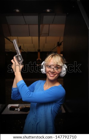 Beautiful young woman with the gun on an indoor shooting range