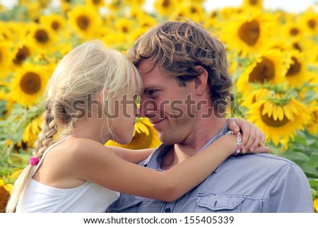 Happy daughter and father hugging on the sunflower field
