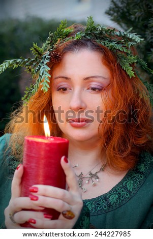 Beautiful woman with the candle and spruce bough wreath. Yule holiday