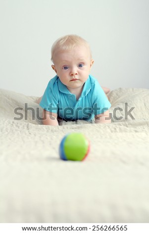 Adorable baby boy with a funny face playing with the little ball
