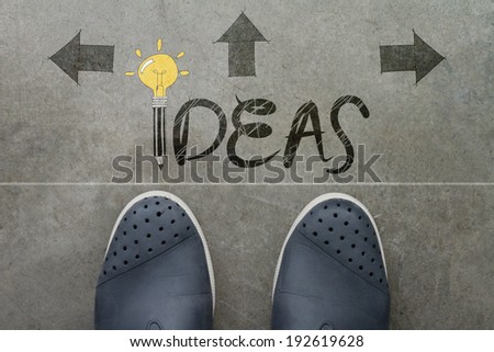 Hand drawn IDEA design word on front of business man feet as concept