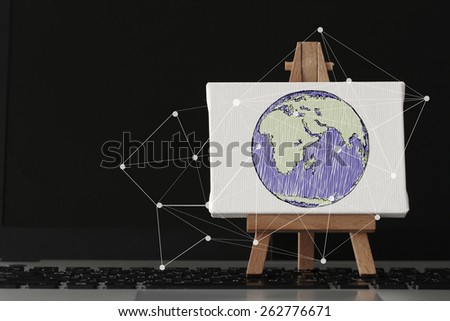 hand drawn globe with social network diagram on canvas and wooden easel on laptop computer as concept