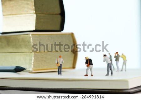 Creative idea concept - miniature photographer with vintage golden book on open paper notebook
