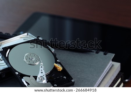 Close up of open computer hard disk drive on desk and notebook