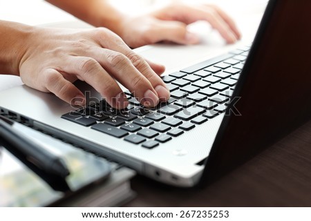 Close up of businessman hand working on laptop computer on wooden desk as concept
