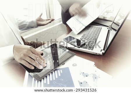 business documents on office table with smart phone and digital tablet and stylus and two colleagues discussing data in the background  with business graph diagram