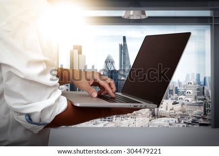 businessman working on his laptop in office with london city background