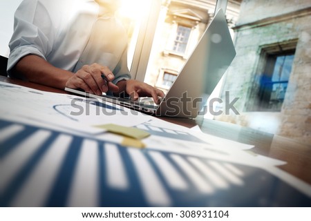 business documents on office table with smart phone and digital tablet and graph financial diagram and man working in the background