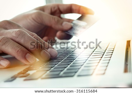 close up of hands using laptop and holding credit card  as Online shopping concept