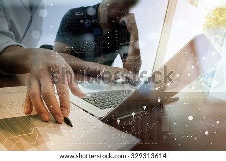 business documents on office table with smart phone and laptop with digital layer effect and two colleagues discussing data in the background