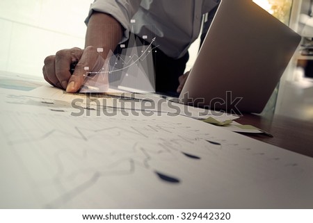 close up of business man hand working on laptop computer with digital layer business graph information diagram on wooden desk as concept