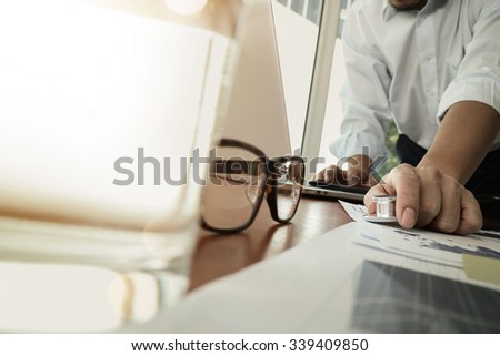 Doctor working at workspace with laptop computer in medical workspace office and digital medical layers diagram with glass of water and eyeglass foreground
