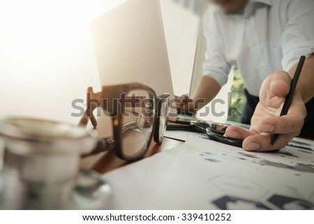 doctor working with laptop computer in medical workspace office and medical network media diagram with stethoscope and eyeglass foreground as concept