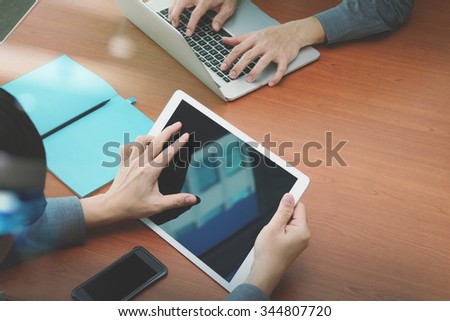 top view of two colleagues discussing data with blank screen new modern computer laptop and pro digital tablet on wooden desk as concept