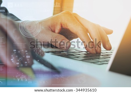 close up of business man hand working on laptop computer with digital layer business graph information diagram on wooden desk as concept