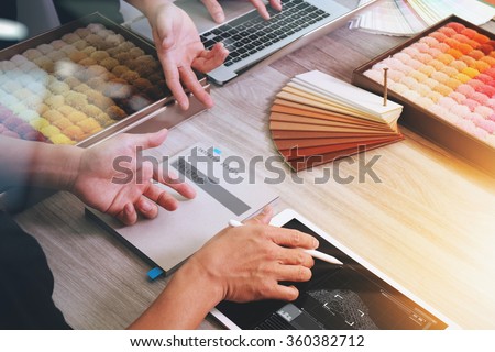 top view of two colleagues interior designers discussing data with new modern computer laptop and pro digital tablet and digital design diagram on screen with sample material on wooden desk as concept