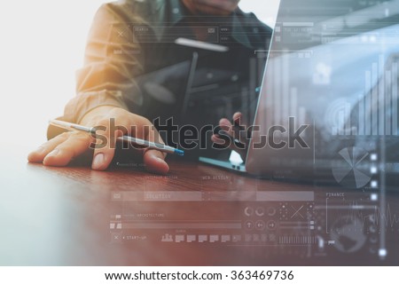 designer hand working and smart phone and laptop and digital business strategy layer effect on wooden desk in office as concept