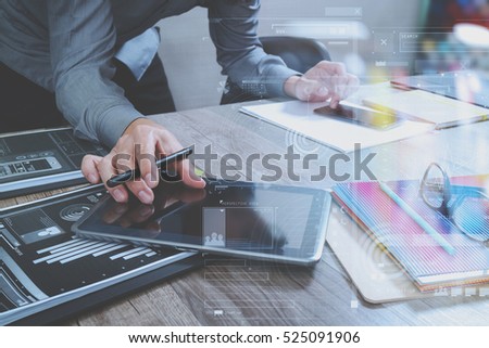 Website designer holding smart phone and working computer digital tablet on wood table,icon graph interface