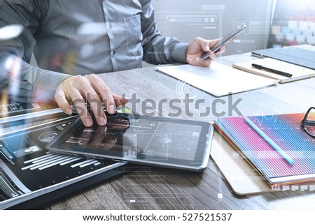 Website designer holding smart phone and working computer digital tablet on wood table,icon graph interface