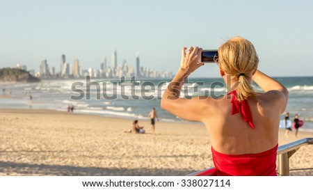 Gold Coast, Female Tourist in red sexy take photo and Out of Focus Surfers Paradise Skyline Q1 Cityscape Coastline Skyscraper Building Beach in Summer Dusk sunset evening, Luxury Resort Spa, Australia