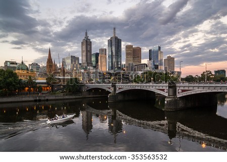 Melbourne City, Reflection CBD Skyline Cityscape, Princes Bridge, Flinders Street railway station from Southbank and Moving Speedboat under Dramatic Sky at Dusk Evening Sunset in Summer, Australia