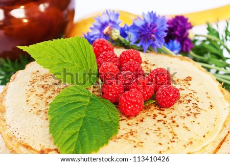 stack of tasty pancakes with berries and leaves of raspberries, bright blue cornflowers