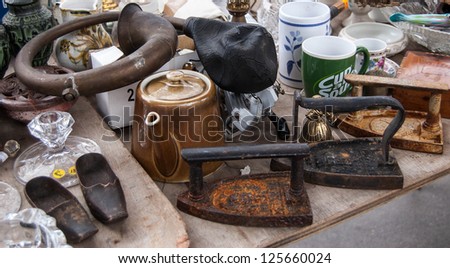PARIS - DECEMBER 29: Three antique irons, klaxon, wooden baby shoes, teapot, mugs for sale at flea market on December 29, 2012 in Paris, France. There are almost 20 flea markets in Paris.