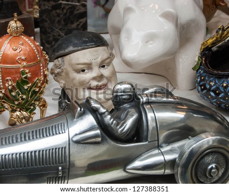 Still life at flea market - toy racing car, laughing man\'s head, bear and ornate egg