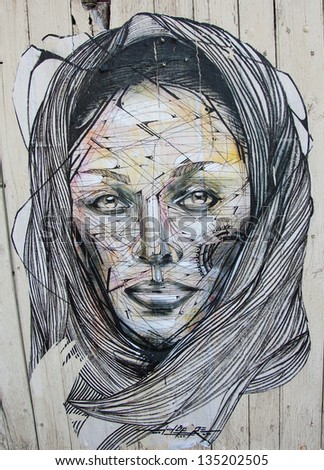 CHARTRES, FRANCE - APRIL 14, 2013: Graffiti portrait of a woman in shawl on the wooden door of an old building. In past decades graffiti became important element of urban culture.