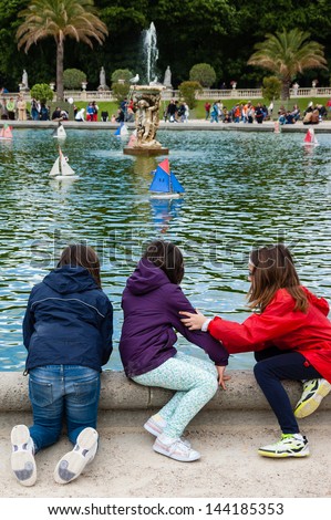 PARIS - JUNE 23: Three unidentified children watch the toy sailing boats in the pond of Luxembourg Gardens on June 23, 2013 in Paris, France. This is the  most popular park in Paris.