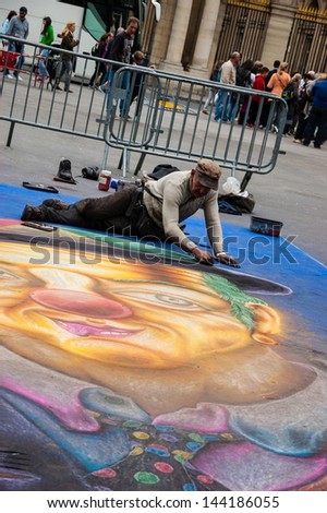 PARIS - JUNE 23: Senior artist during drawing funny clown on sidewalk near Palais Royal on June 23, 2013 in Paris, France. In past decades street art became important element of french urban culture.