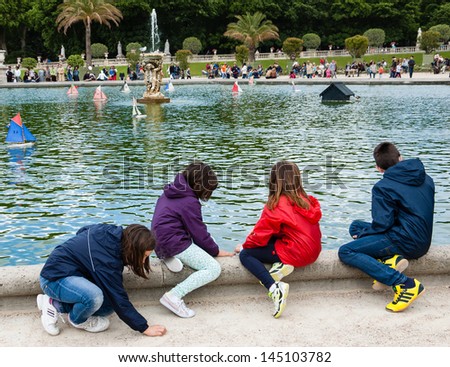PARIS - JUNE 23: Four unidentified children watch the toy sailing boats in the pond of Luxembourg Gardens on June 23, 2013 in Paris, France. This is the  most popular park in Paris.