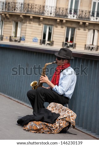 PARIS - JULY 6: Unidentified young saxophone player on the bridge as seen on July 6, 2013 in Paris, France. Dozens buskers perform on the streets and in the metro of Paris.