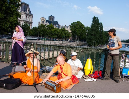 PARIS - JULY 6: Unidentified members of Hare Krishna play music and sing on the bridge near Louvre July 6, 2013 in Paris, France.