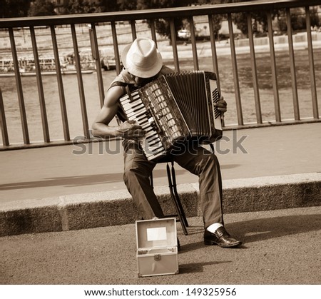 PARIS - JULY 6: Unidentified senior musician play accordion on the bridge on July 6, 2013 in Paris, France. Dozens buskers perform on the streets and in the metro of Paris.
