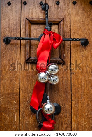 Christmas decoration on the wooden door. Red ribbon and four silver balls with street reflection.