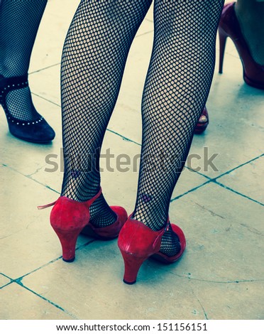 Retro style. Heart shape tattoo on sexy legs, vintage shoes and fishnet pantyhose. Aged photo.