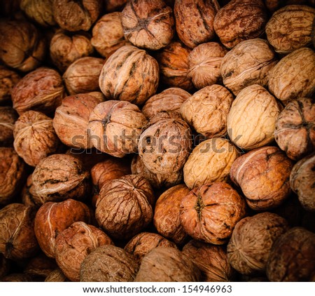 Closeup of walnuts in shell at the farmers market in Paris. Walnuts stacked one upon the other. Shadowed angles.