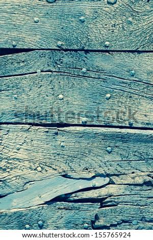 Old turquoise wooden texture with nail heads and cracks.