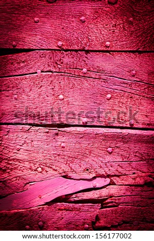 Old magenta wooden texture with nail heads and cracks. Shadowed angles.