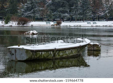 Snow covered boat in the lake.  Lake Daumesnil (Vincennes forest, Paris, France).