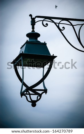Vintage lantern with water drops after rain and lonely bird at backgrounds. Loneliness concept. Shadowed angles.
