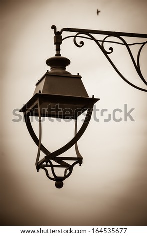 Vintage lantern with water drops after rain and lonely bird at backgrounds. Loneliness concept. Sepia. Shadowed angles.