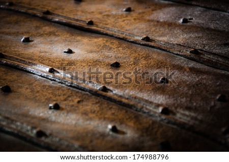 Surface of the old rusty bound chest with rivets and nail heads. Light and shadow game. Vintage background.