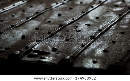 Surface of the old rusty bound chest with rivets and nail heads. Light and shadow game. Vintage background.